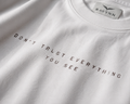 RAVYNN Oversized White T-Shirt – "Realistic / Don't Trust Everything You See" Sculpture Back Graphic